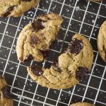 Homemade Brown Butter Chocolate Chunk Cookies arranged on a cooling rack in a rustic baking scene.