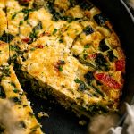 Garden zucchini frittata cut into wedges in a cast iron skillet with a golden top and tender vegetable filling.