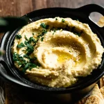 Classic homemade hummus topped with olive oil and fresh herbs
