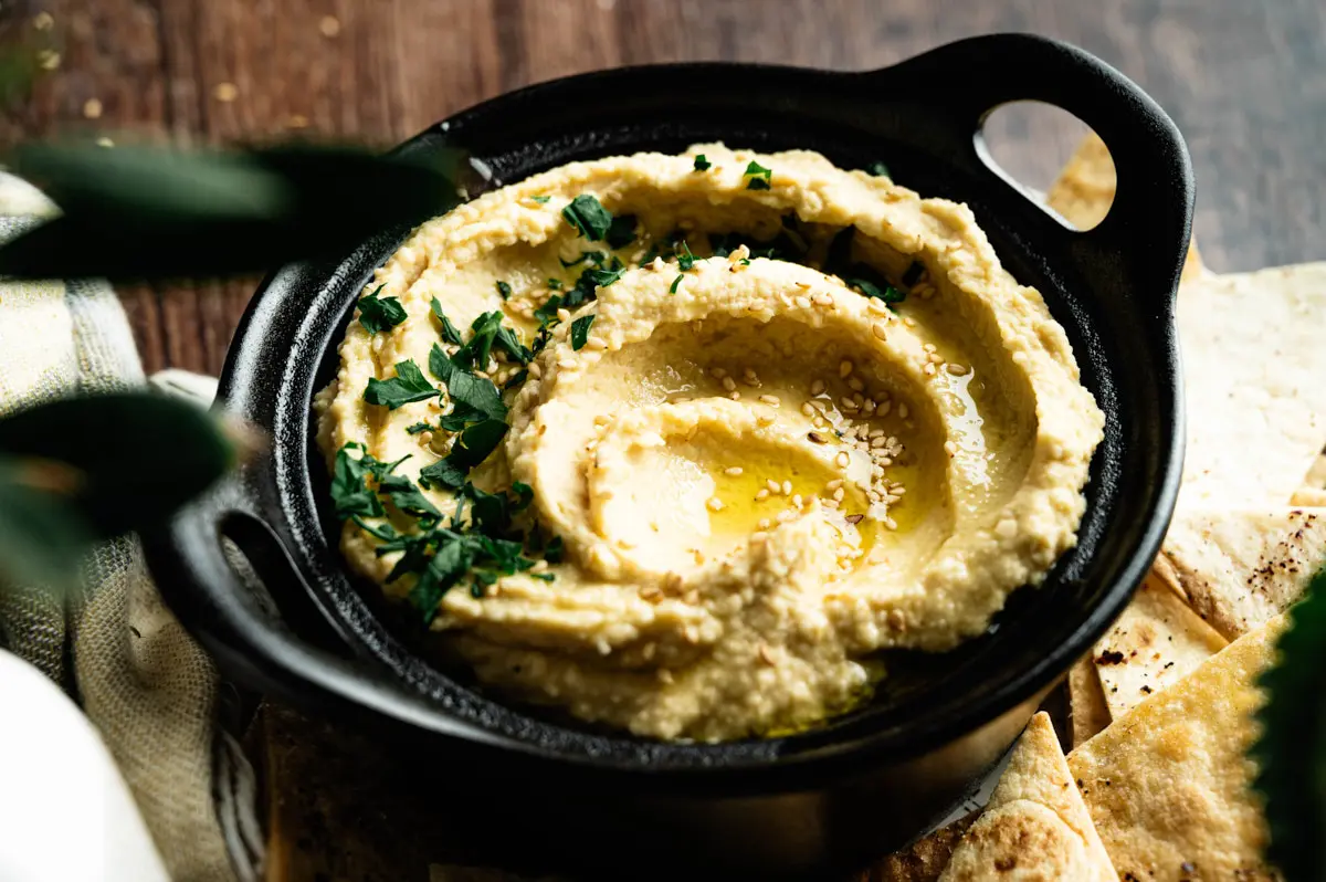 Classic homemade hummus topped with olive oil and fresh herbs
