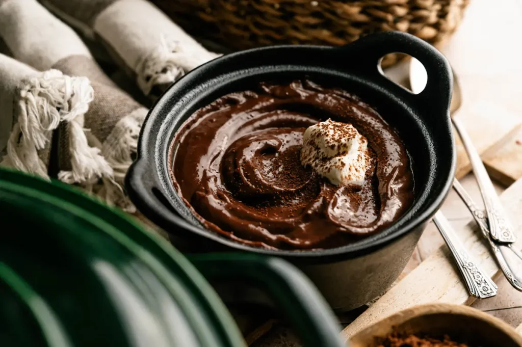Homemade chocolate pudding being garnished in a black serving bowl