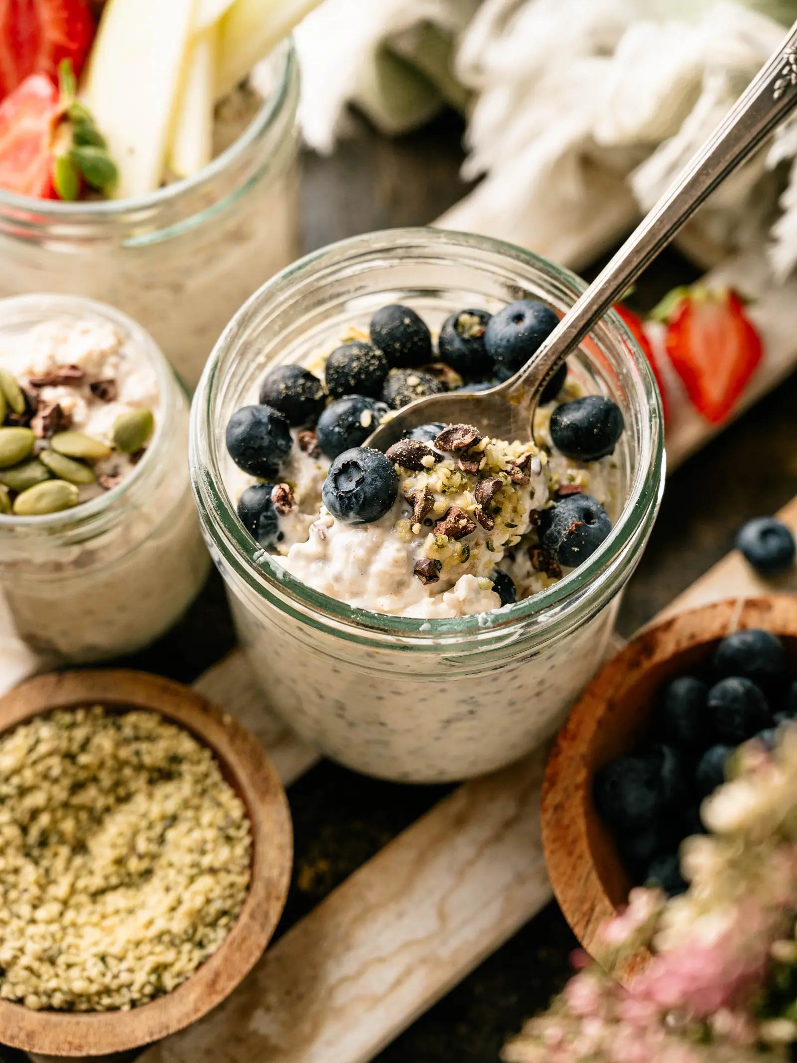 Kefir overnight oats in jars topped with blueberries, pumpkin seeds, and fresh fruit